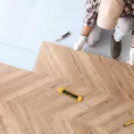 A construction worker installing laminate wooden floor indoors as a tenant improvement, above view
