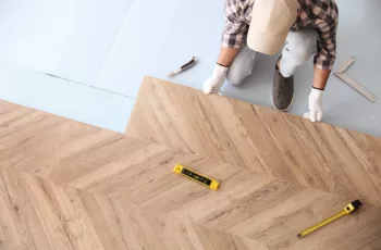 A construction worker installing laminate wooden floor indoors as a tenant improvement, above view