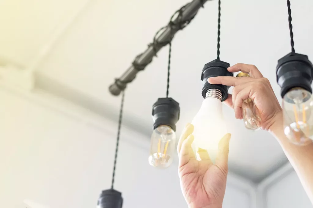 A hand replacing outdated light bulbs with LED lightbulbs 