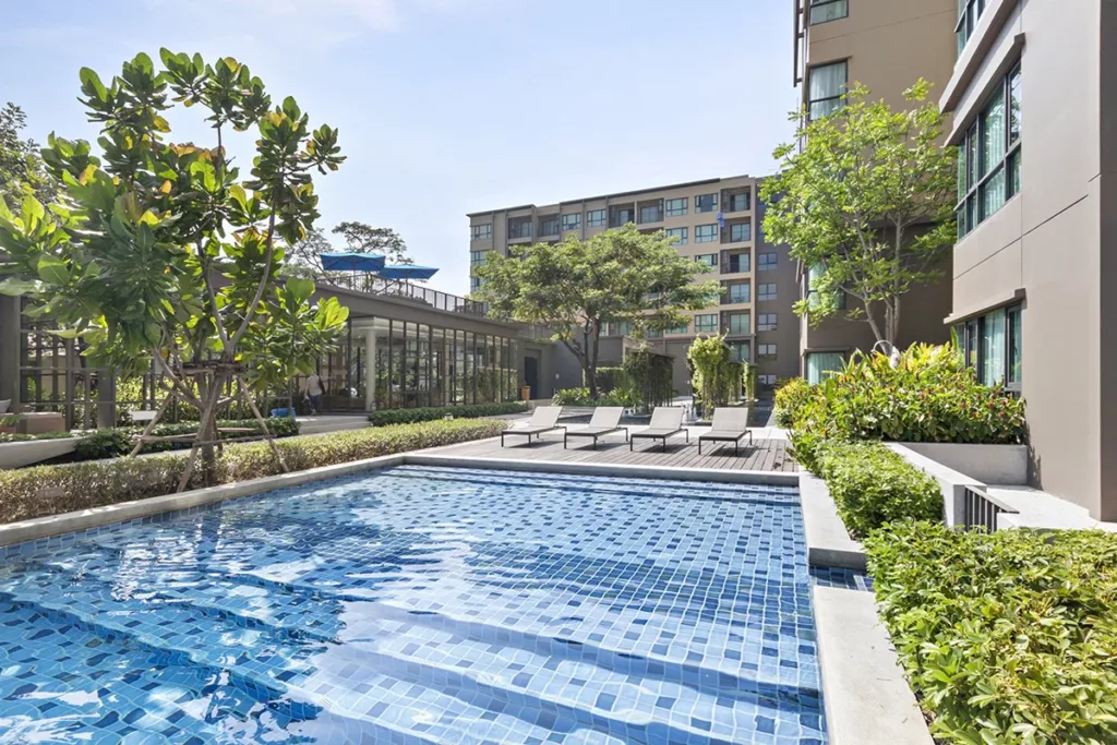 A swimming pool in a modern apartment complex, surrounded by trees