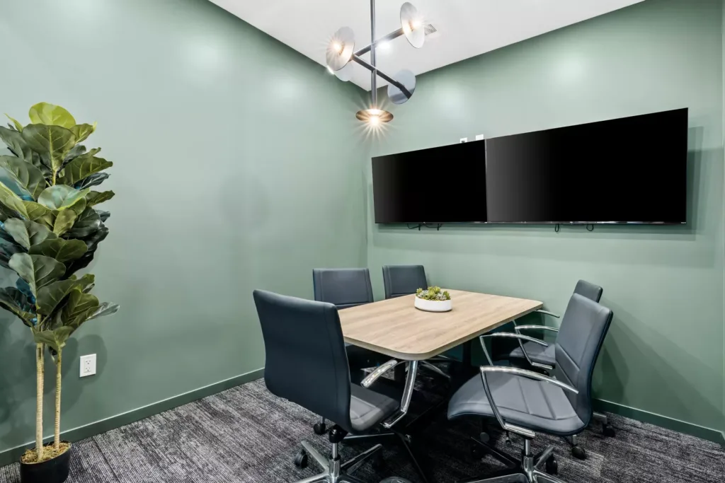 Open and well lit conference room with two televisions, a table, and chairs